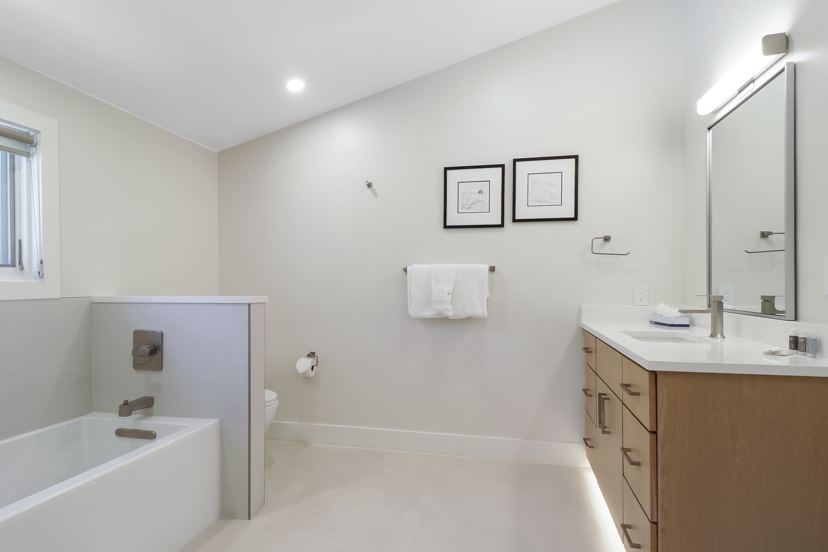 Step into your private spa-like retreat with a soaking tub, walk-in shower, and modern vanity where crisp white linens await your refreshing escape.