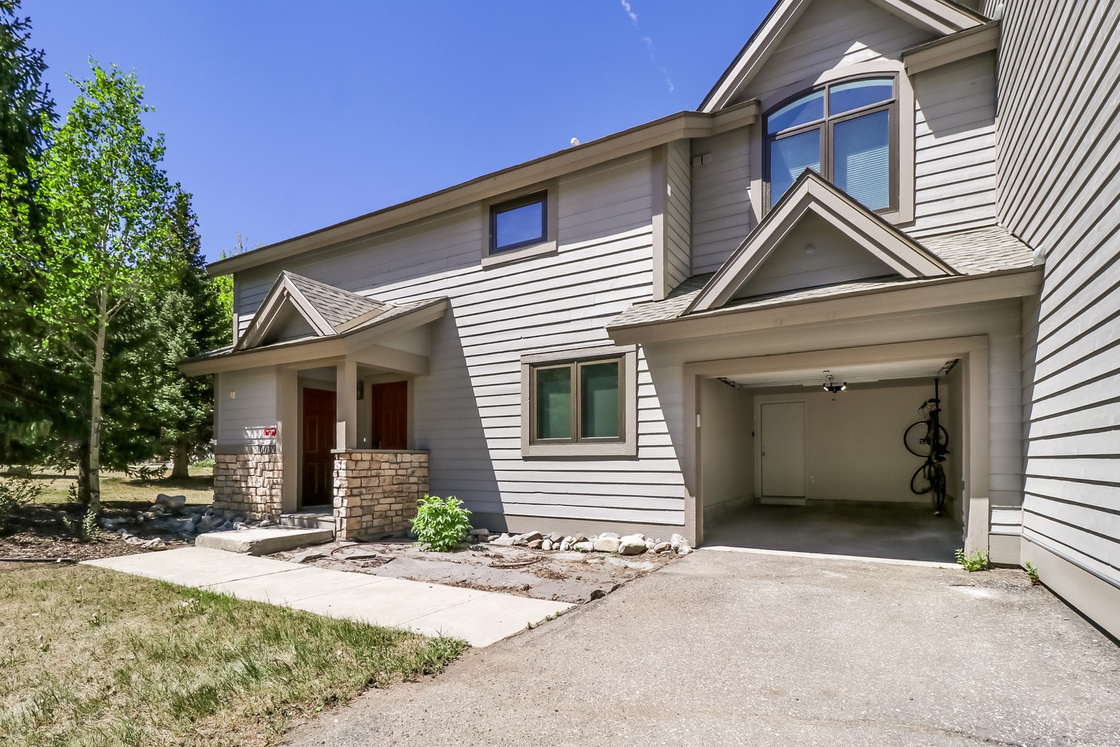 A welcoming two-story vacation home with ample parking, nestled in a quiet neighborhood with mature trees and a peaceful setting.