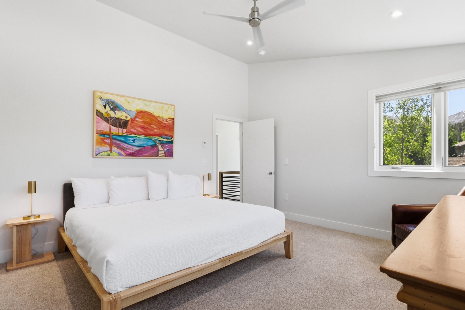 Drift off in crisp, comfortable bedding surrounded by calming tones, vibrant artwork, and mountain views from your window—your peaceful retreat after a day of adventure.