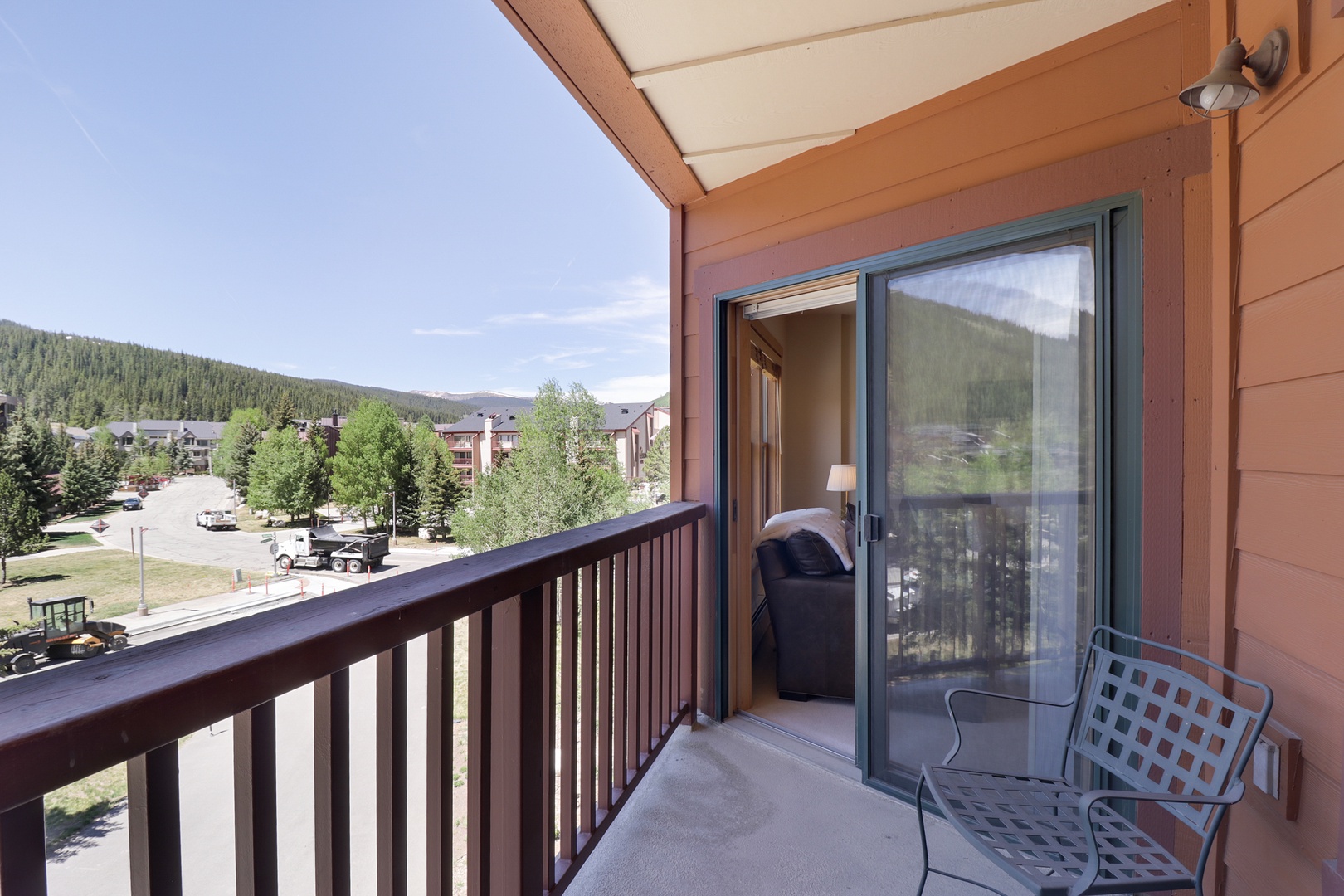 Private balcony overlooking tree-lined mountain neighborhood, ideal for morning coffee or evening relaxation with scenic forested slopes in the distance.