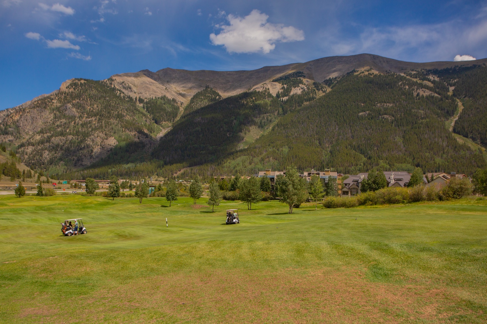 The property is set against stunning mountain scenery with a golf course and natural landscape nearby.