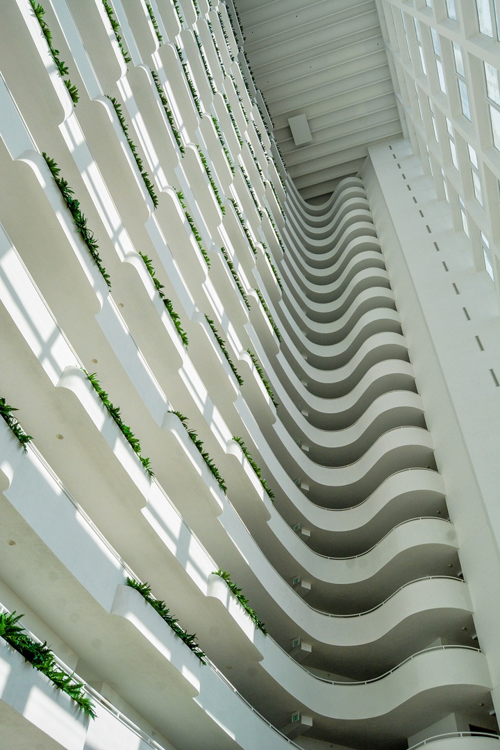 Marvel at the stunning atrium architecture with its flowing balconies and natural light filtering through this modern space.