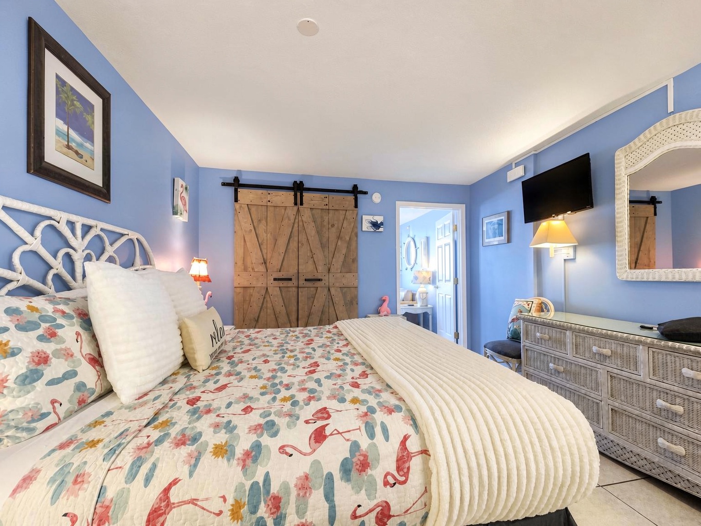 Drift into relaxation in your tranquil coastal bedroom, where soothing blue walls and playful tropical accents create the perfect beach-inspired sanctuary for your getaway.