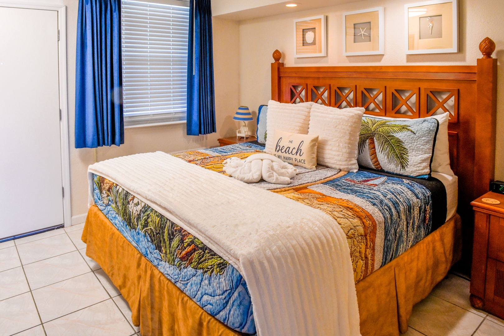 Sink into your coastal retreat with a plush bed dressed in beach-inspired linens, warm wood accents, and calming blue tones that invite restful nights by the shore.