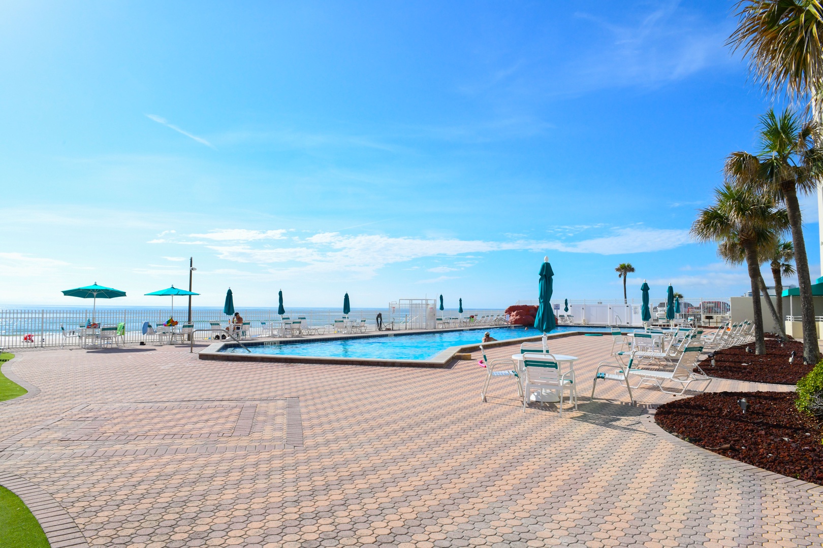 Beachfront pool deck with stunning ocean views, swaying palms, and plenty of sun loungers—your perfect spot to soak up the Florida sun and unwind.