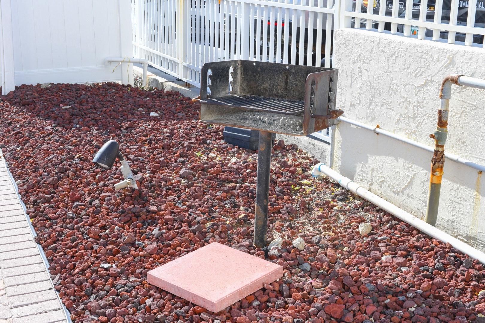 Outdoor barbecue area with a sturdy metal grill set in a rustic, landscaped courtyard—perfect for grilling fresh meals under the sun.