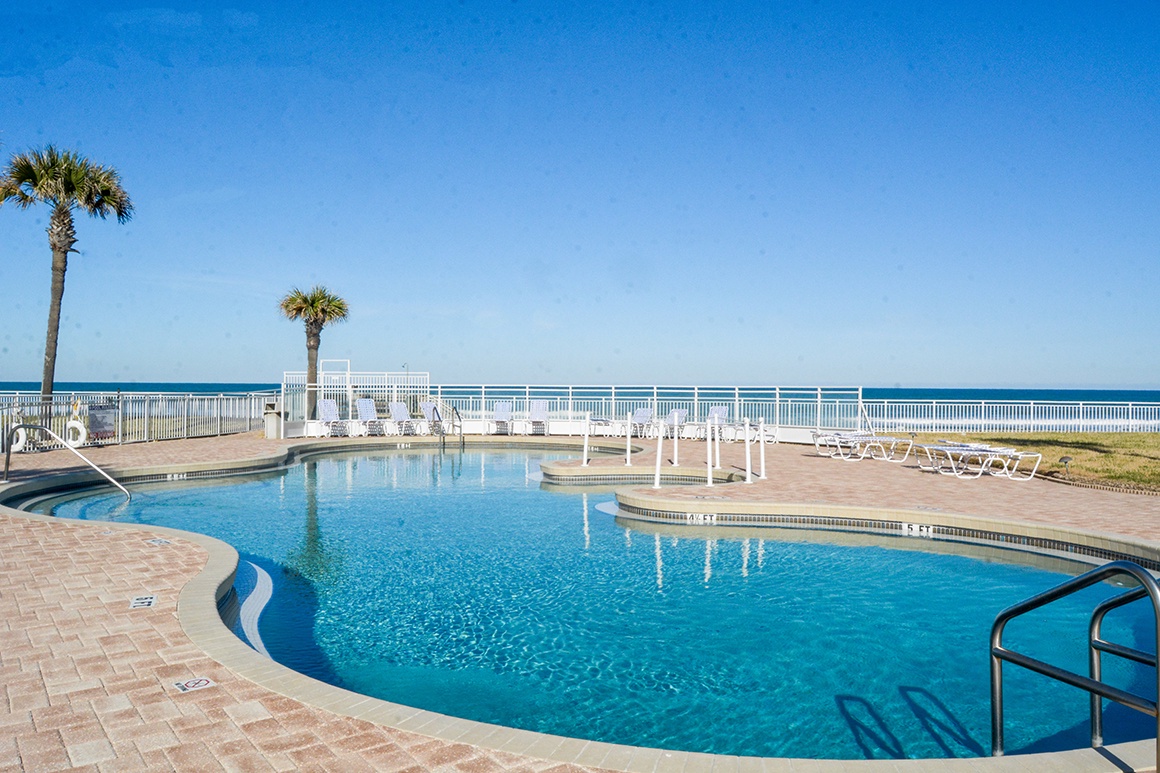 Sparkling oceanfront pool awaits your morning swim, with pristine waters reflecting endless blue skies and swaying palms.