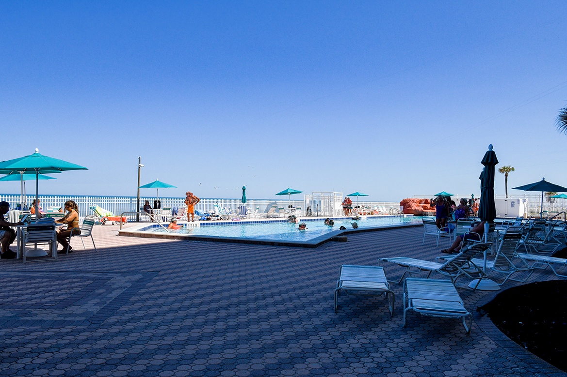 Poolside paradise awaits with comfortable loungers and turquoise umbrellas under endless blue skies.