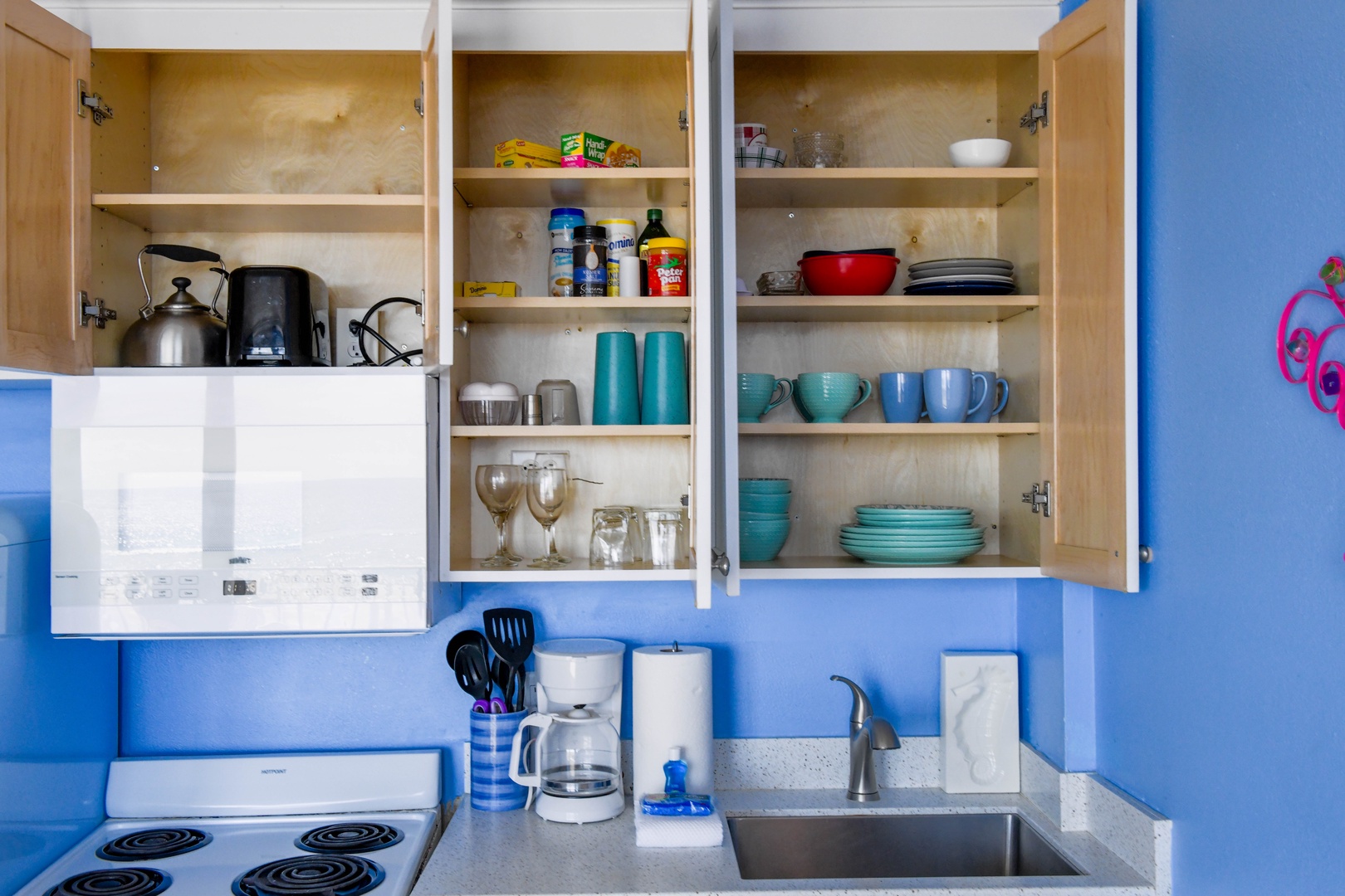 Your fully-equipped kitchen has everything you need to cook and serve meals during your stay, with colorful dishes, glassware, and cookware neatly arranged and ready for your use.