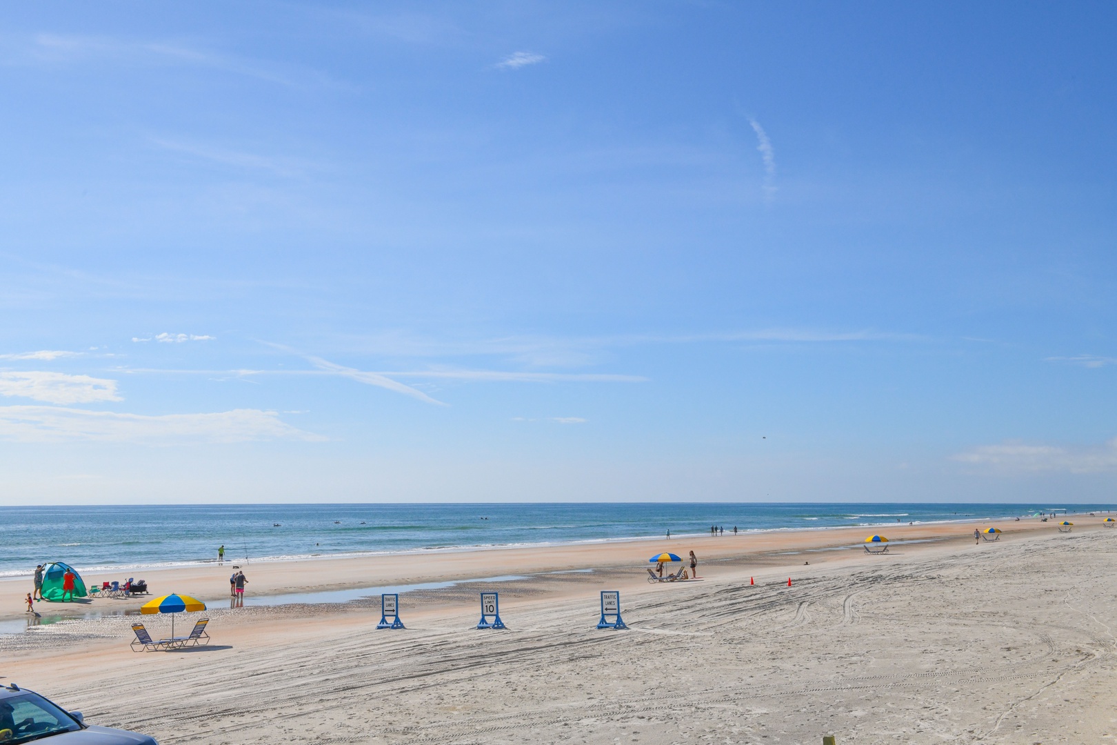 Wide sandy beach stretches along calm ocean waters under clear blue skies, offering a peaceful coastal setting near the property.