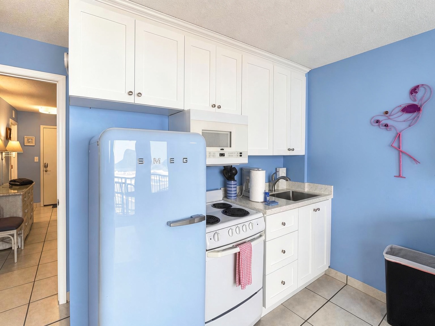 Your kitchen pops with cheerful retro style, featuring a vintage-inspired powder-blue fridge and bright coastal walls. Crisp white cabinets, a full stove, and modern touches make cooking a breeze in this fun, functional space.