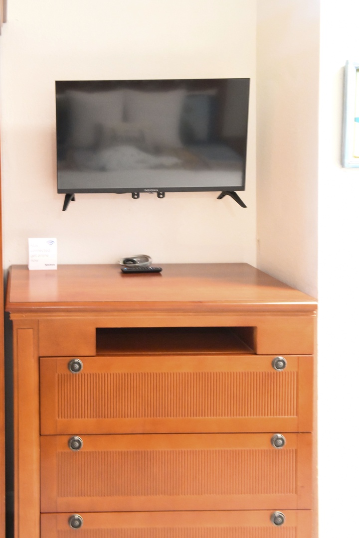 Your room features a wall-mounted flat-screen TV and a beautifully crafted wooden dresser with ample drawer space for storing your belongings during your stay.