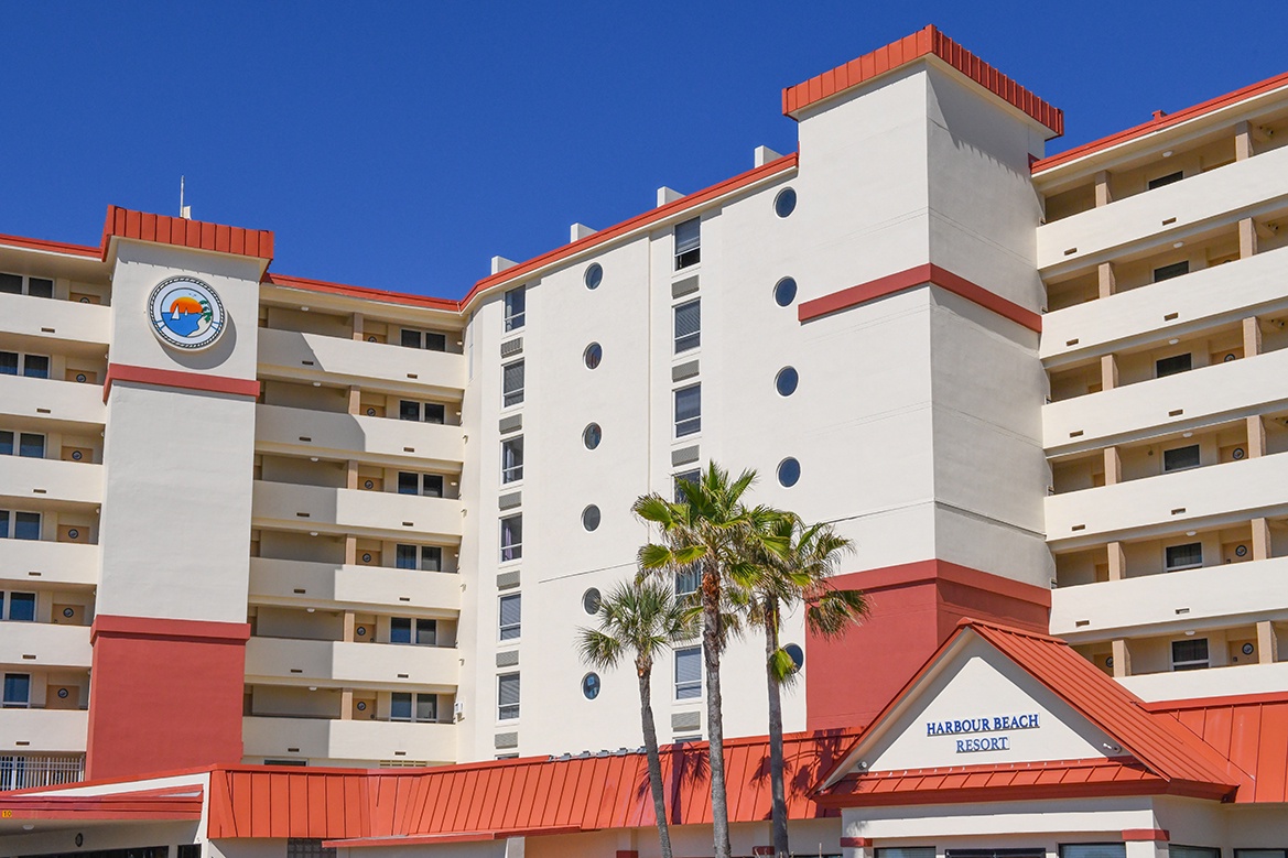Harbour Beach Resort welcomes guests with distinctive architecture and tropical palm trees under brilliant blue skies.