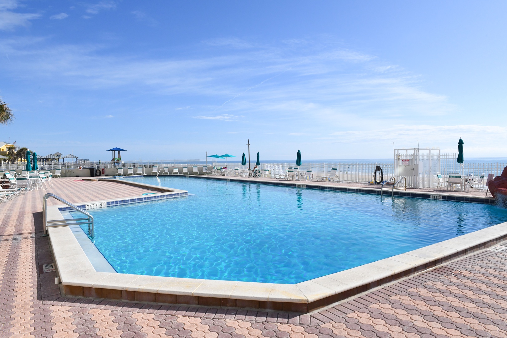 Sparkling beachfront pool framed by coastal views and sunny skies—perfect for peaceful swims and soaking up the oceanside ambiance.