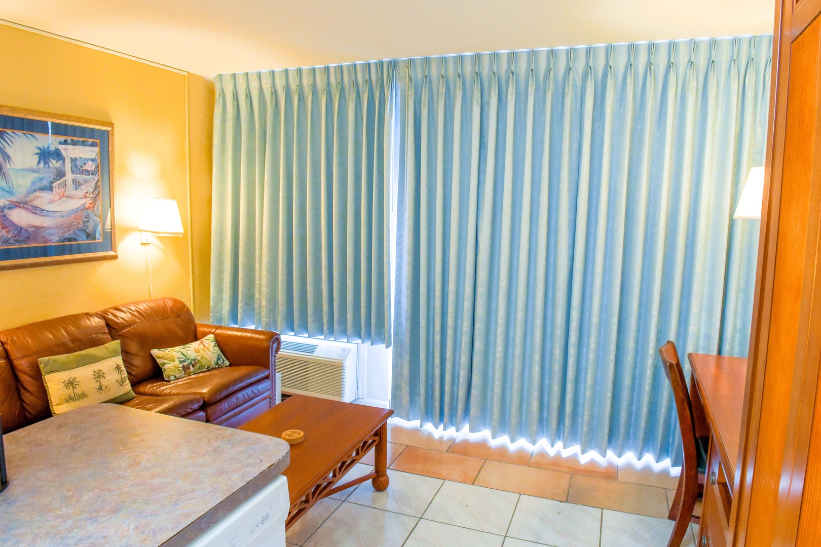 Settle into your cozy living space with comfortable leather seating, warm tropical accents, and plenty of natural light filtering through floor-to-ceiling windows—your perfect home base for island adventures.