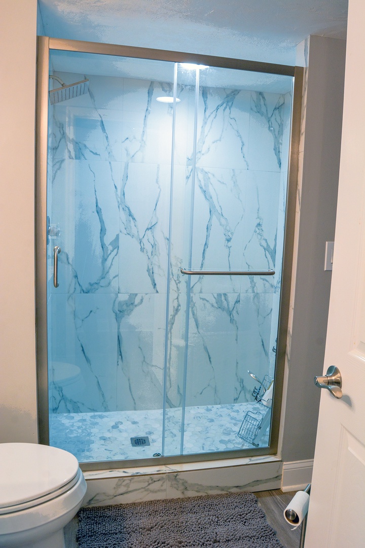 Step into your stunning marble-inspired shower with sleek glass doors and modern fixtures for a spa-like experience.