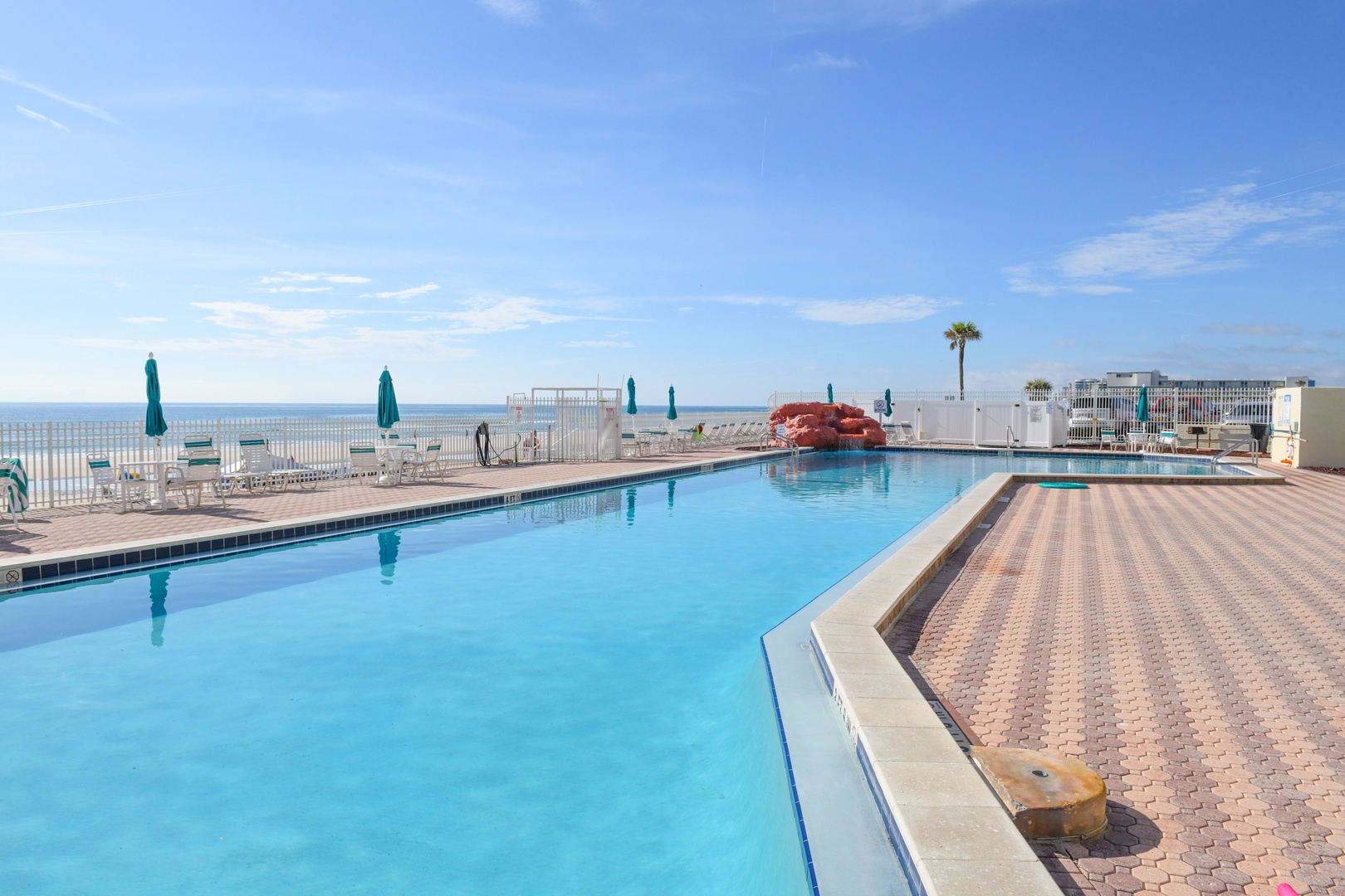 Sparkling oceanfront pool awaits with sun loungers, umbrellas, and a coral-colored water slide. Pristine blue waters meet endless Gulf views while you soak up the coastal sunshine.