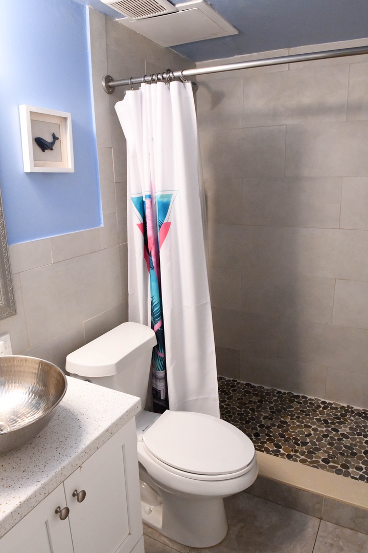 Your private bathroom features a modern walk-in shower with natural stone accents, soothing blue walls, and a vanity to prepare for each day's adventure.
