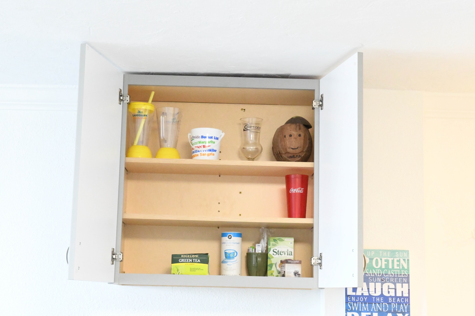 A well-organized cabinet stocked with essentials like teas, beverages, and drinkware—everything you need to enjoy a refreshing morning coffee or evening drink.