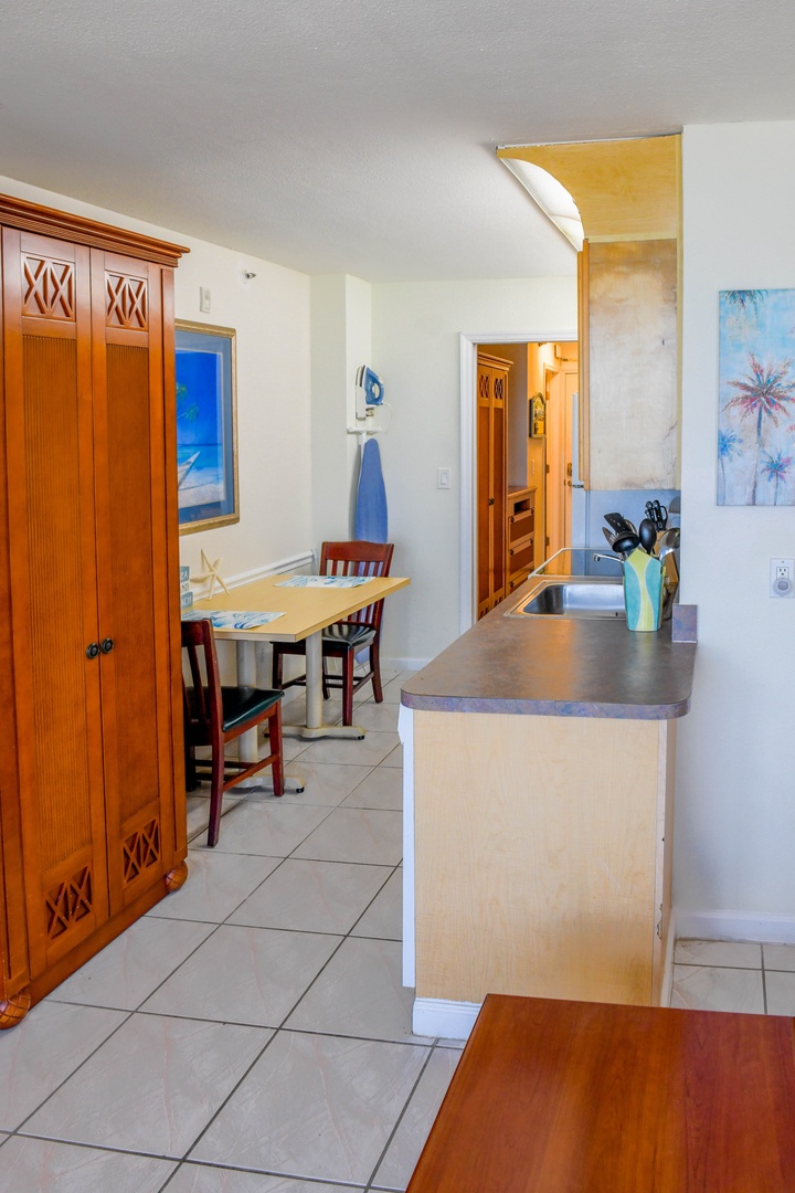 Open kitchen and dining area with coastal décor, inviting you to enjoy casual meals in a light-filled, beachy setting with tropical-inspired art.
