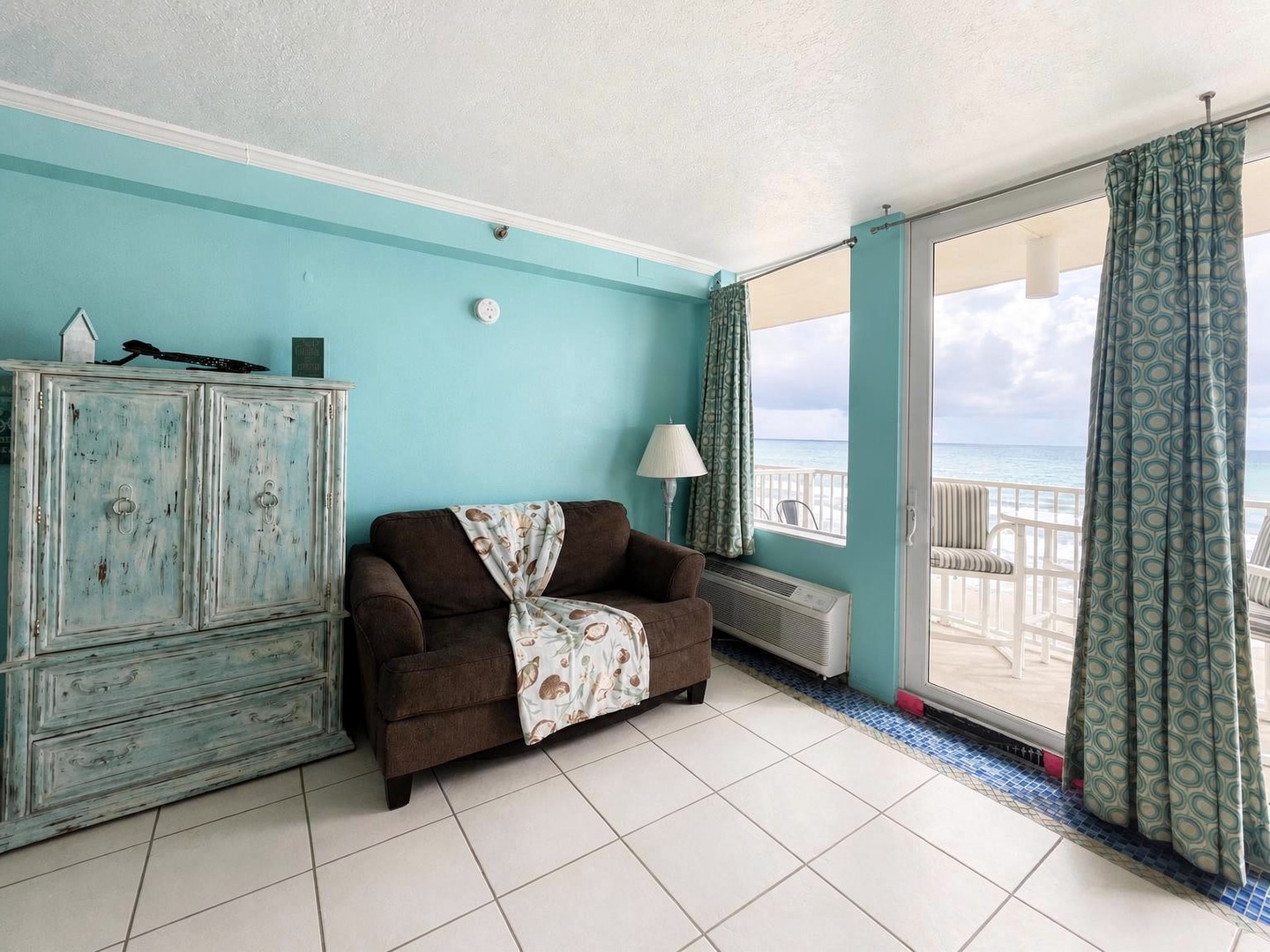 Step into your coastal living space where the ocean is just beyond your private balcony, with calming turquoise tones and a cozy spot to unwind after beach adventures.