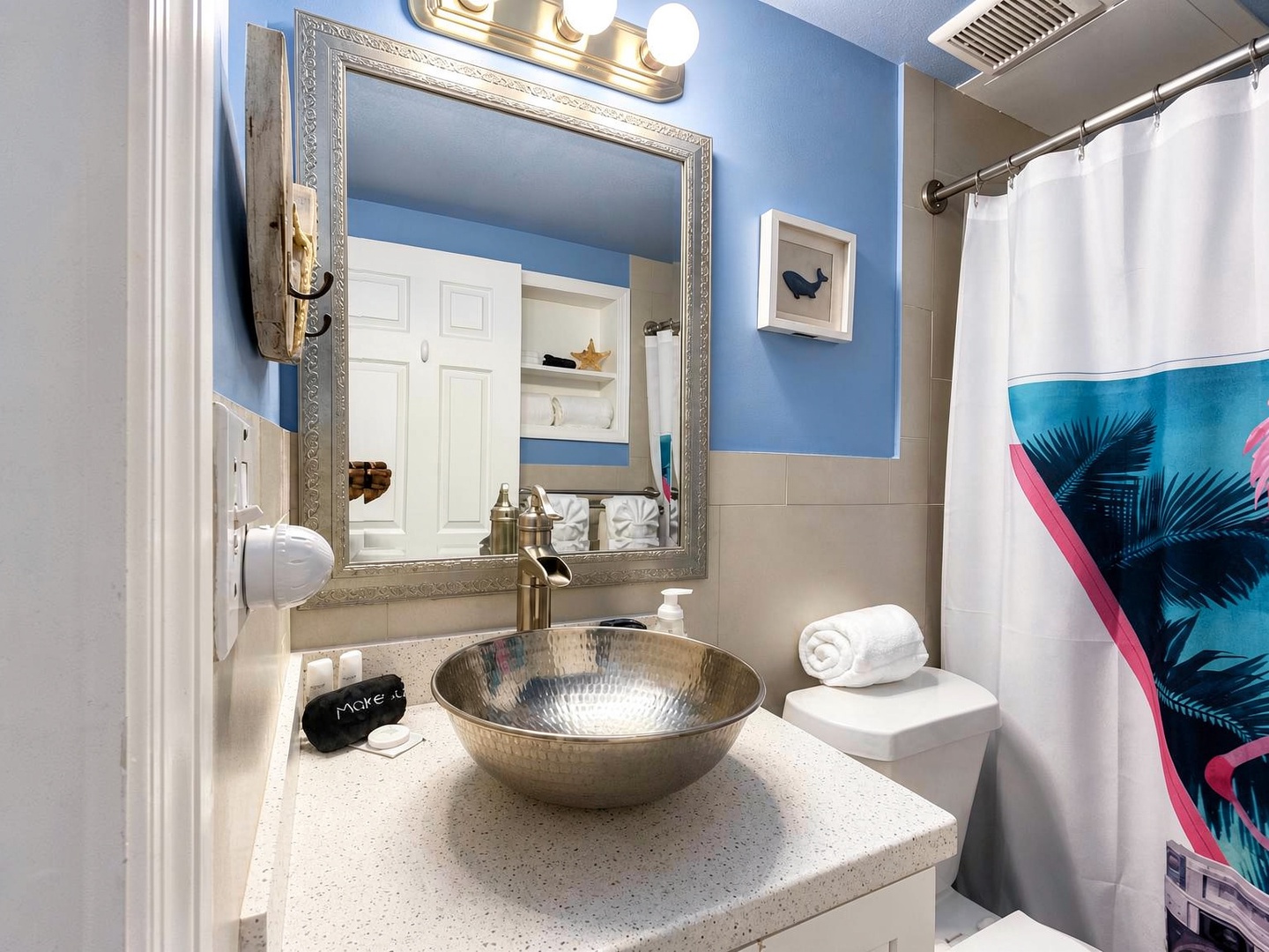Freshen up in your coastal-inspired bathroom featuring a stylish hammered metal sink, vibrant blue walls, and beachy touches that'll have you feeling relaxed before you even step into the shower.