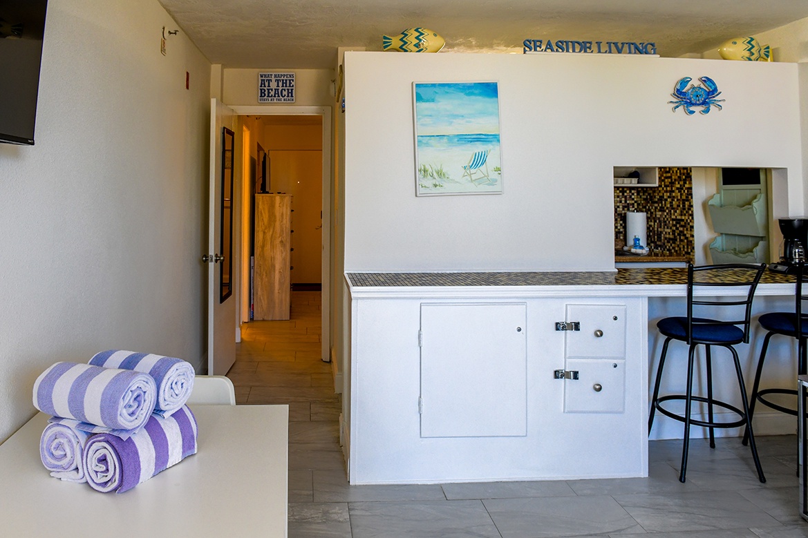 Your coastal retreat features a cheerful kitchen island with purple striped towels ready for your beach adventures.