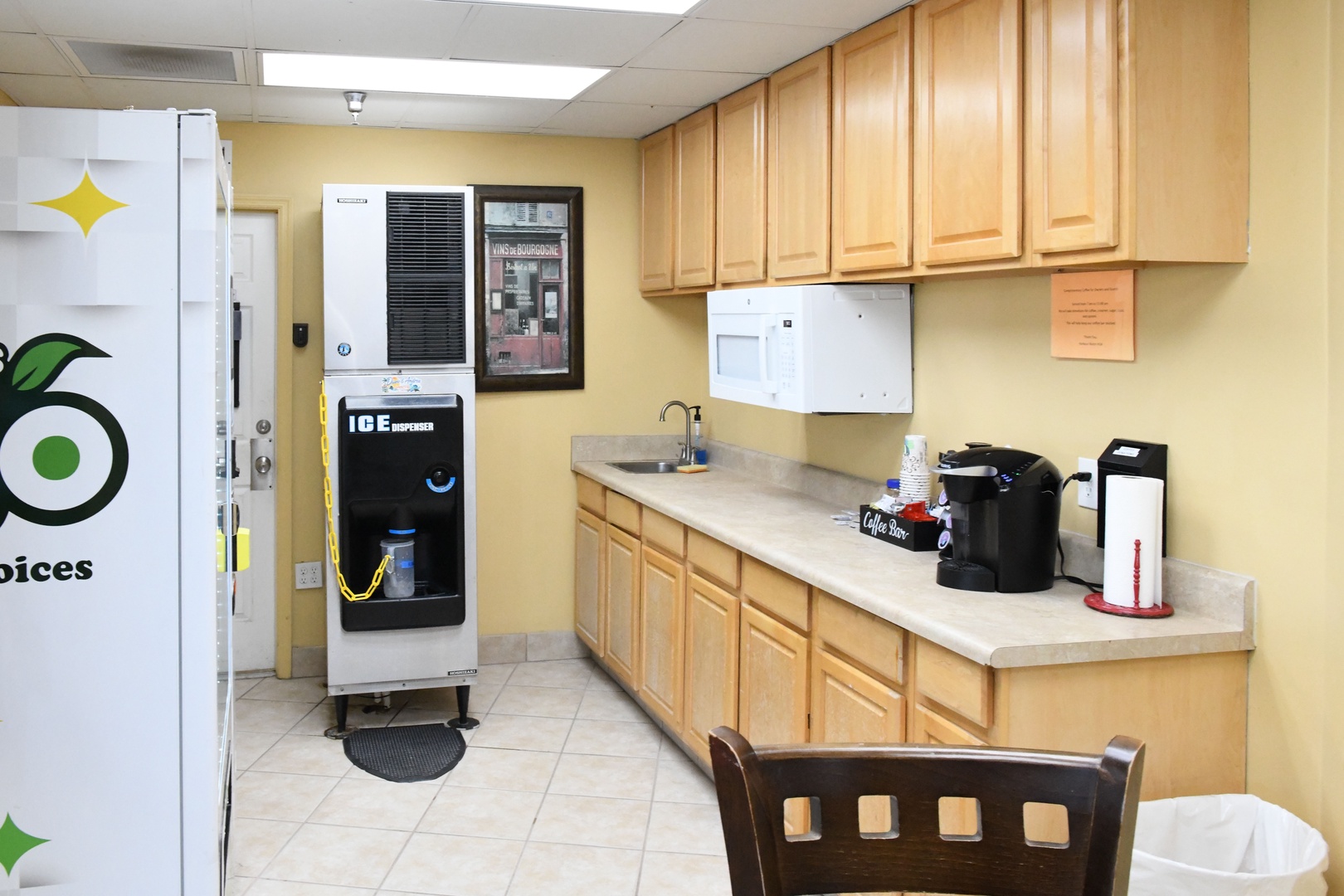 Communal kitchen with maple cabinetry, ice dispenser, coffee station, and dining seating—ready to support your group gatherings and meal prep.