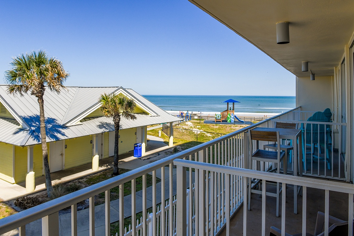 Beachfront property balcony offering direct ocean views with playground and sandy shoreline visible from the covered outdoor space.