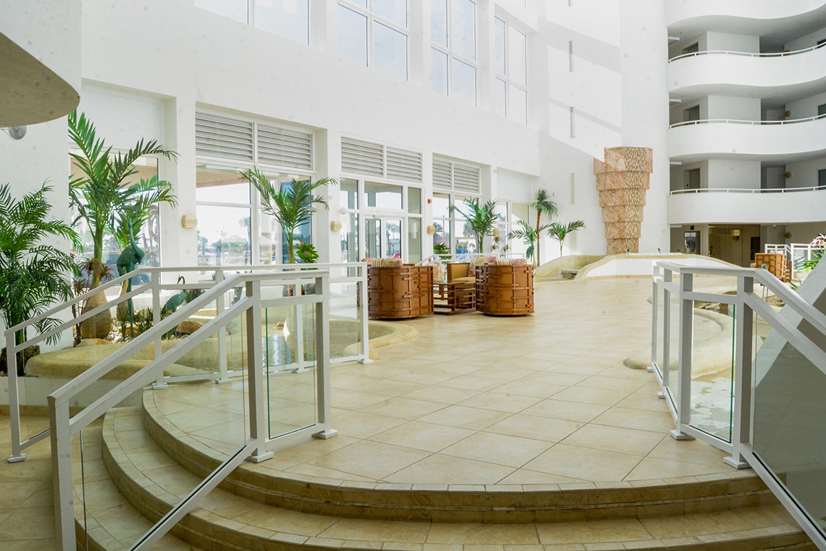 Step into this stunning multi-level lobby where tropical palms and modern design create your perfect vacation welcome.