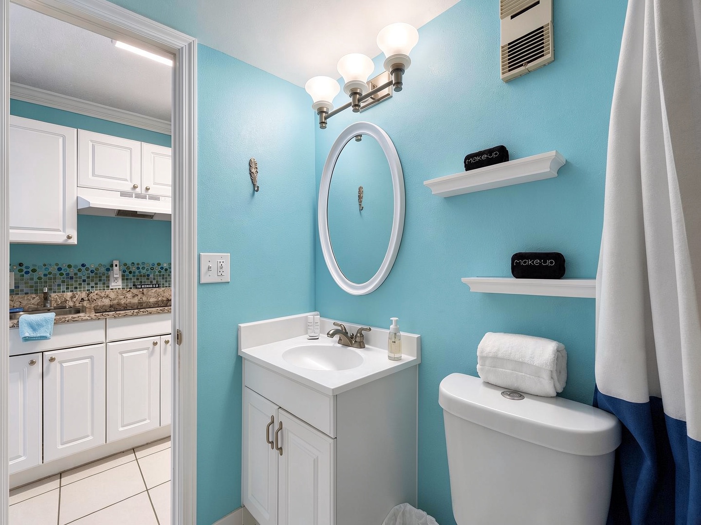 Your private bathroom features a bright coastal vibe with fresh white fixtures, a stylish oval mirror, and thoughtful touches like floating shelves and soft lighting to help you feel right at home.