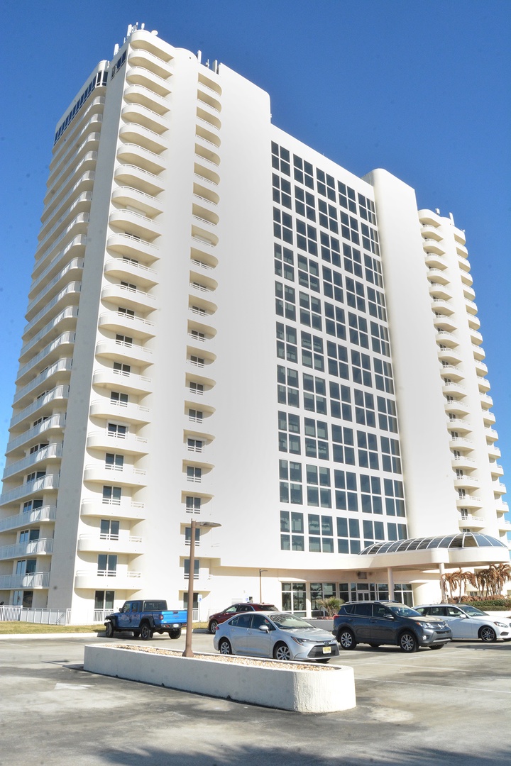 Modern white high-rise property features curved balconies and convenient parking facilities.