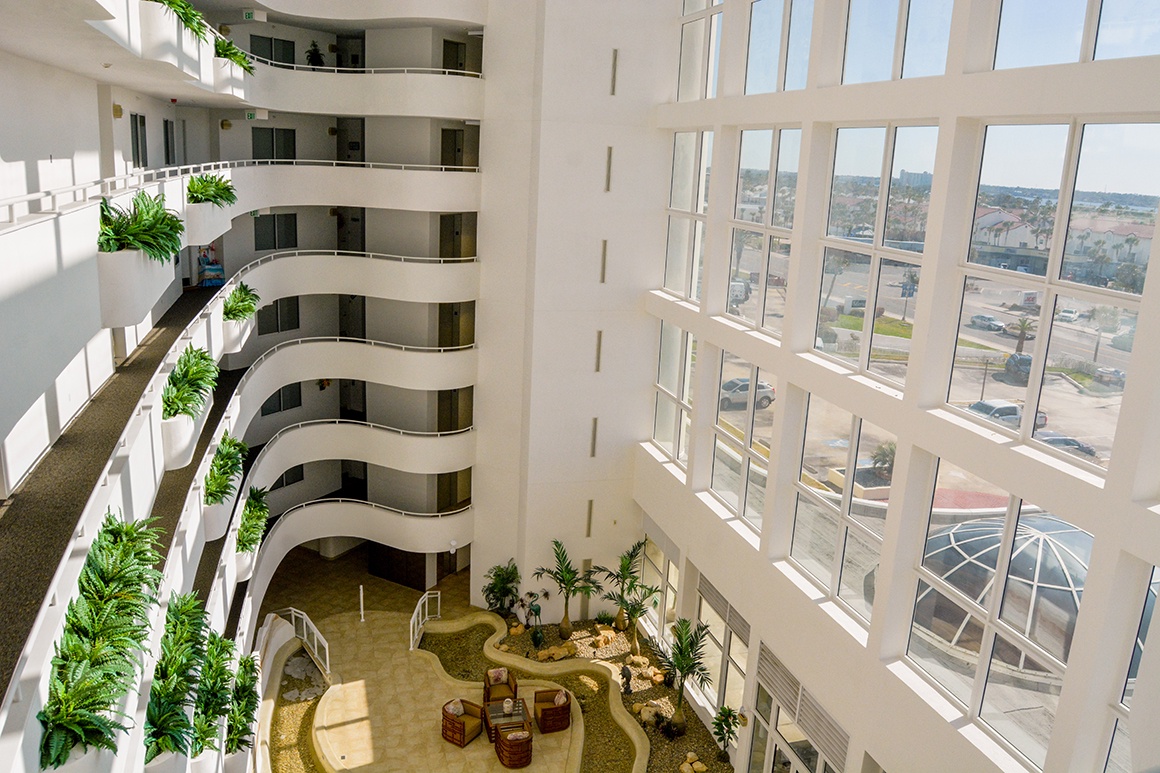 Step into a stunning atrium with soaring windows and lush greenery creating a peaceful retreat above the vibrant cityscape.
