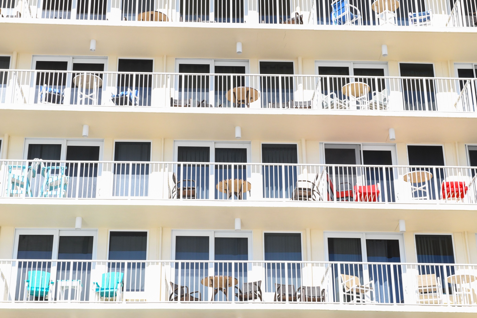 Beachfront building with multiple levels of private balconies, each offering outdoor seating for guests to relax and enjoy coastal views.