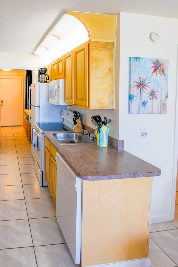 Step into your fully equipped galley kitchen with everything you need to prepare meals—stainless steel sink, smooth countertops, and tropical charm in every corner.