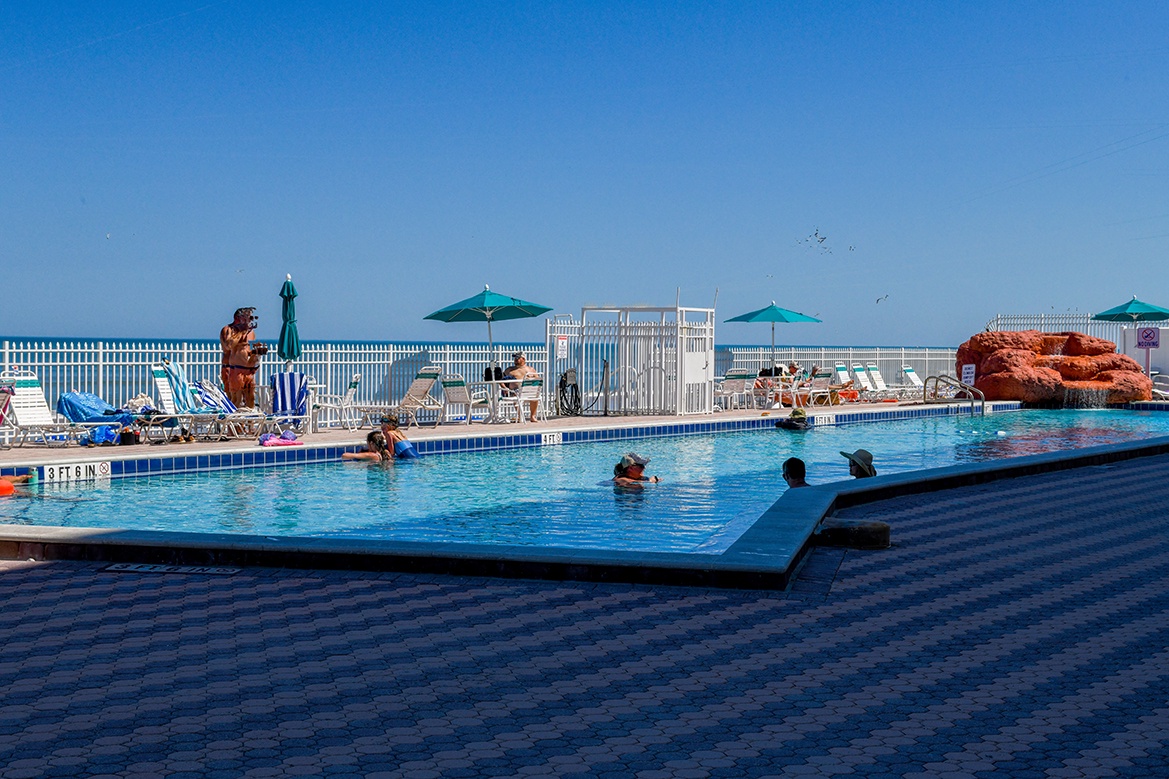 Dive into crystal-clear waters surrounded by comfortable lounge chairs and shaded umbrellas for your perfect poolside retreat.