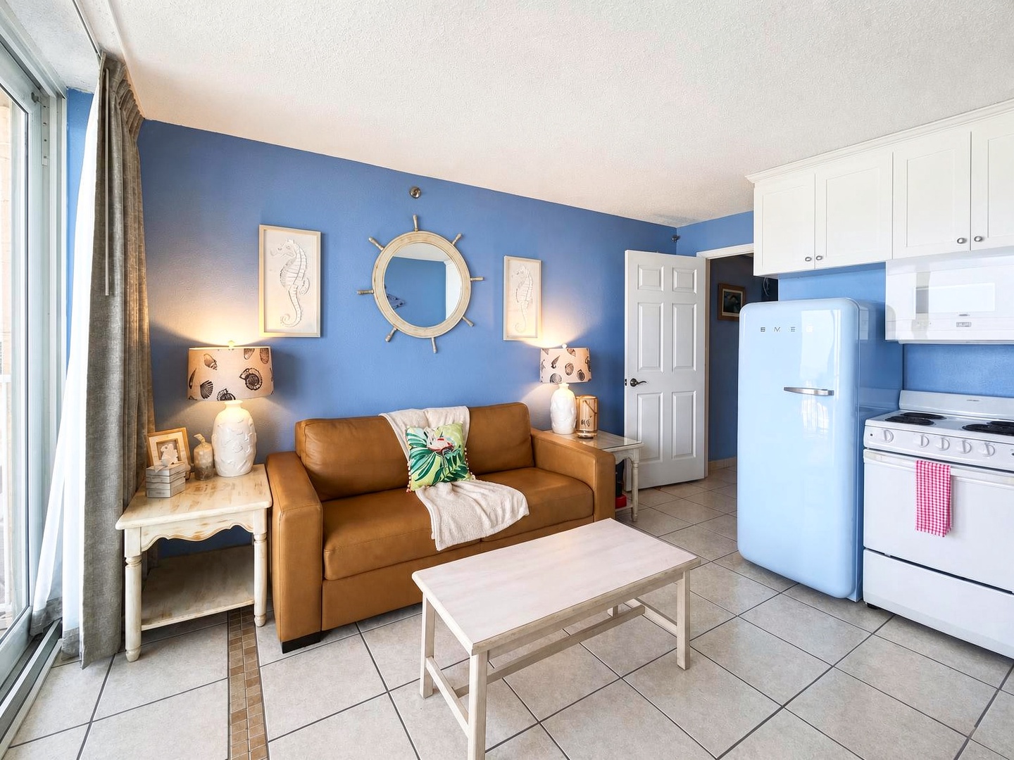 Relax in your bright coastal-inspired living space, where nautical touches and a cozy sofa invite you to unwind. Your fully equipped kitchen awaits for easy meal prep, and natural light fills the room.