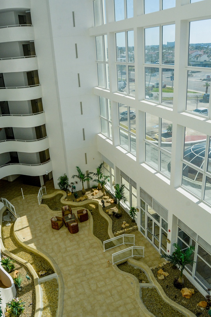 The soaring lobby welcomes you with dramatic floor-to-ceiling windows and peaceful garden paths winding through indoor greenery.