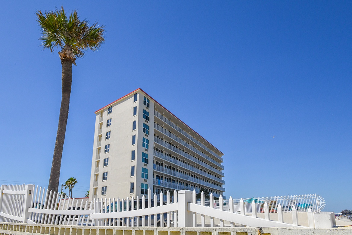 Beachfront property featuring modern architecture and tropical palms under clear blue skies, perfectly positioned for your coastal getaway.