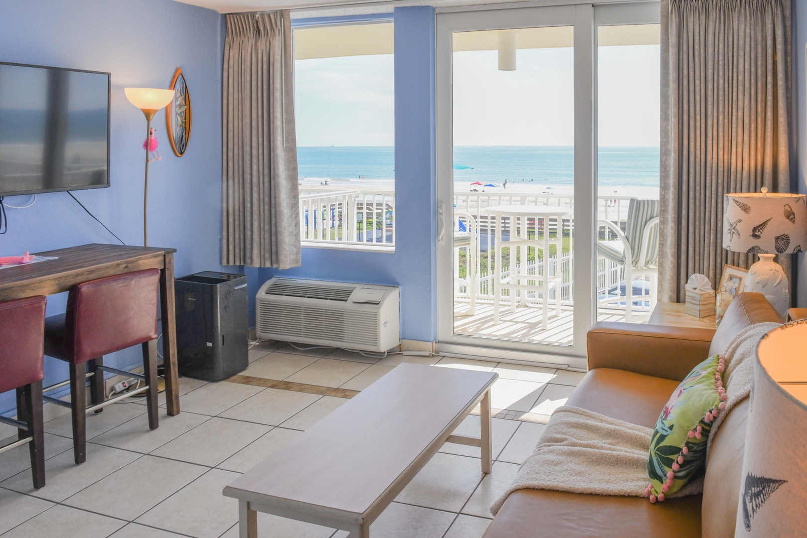 Your living space opens to a balcony overlooking white railings, soft sand, and sparkling ocean waves—perfect for morning coffee or sunset watching.