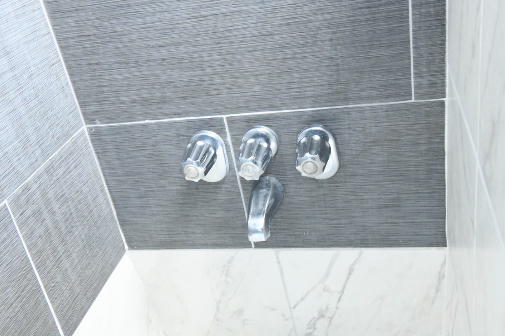 Sleek modern fixtures meet elegant dark tiling, creating a spa-like atmosphere where you can refresh and unwind in style.