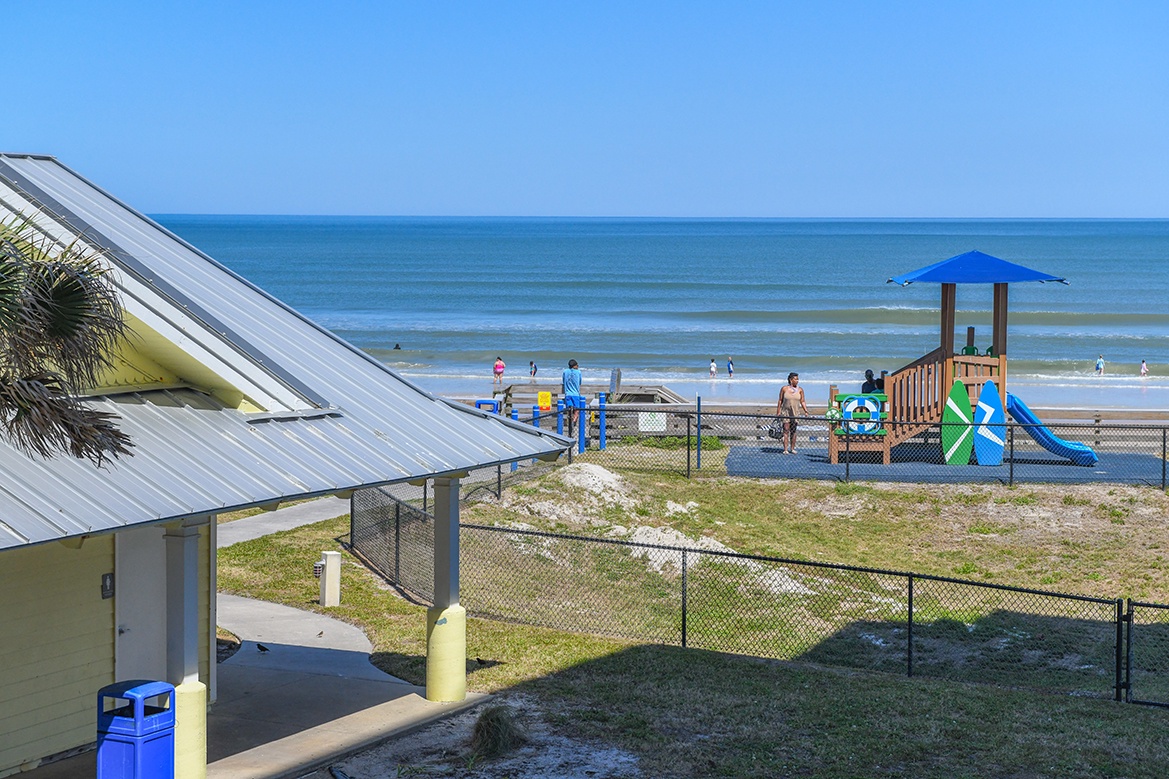 Beachfront property with playground and direct access to golden sand beaches and gentle ocean waves.