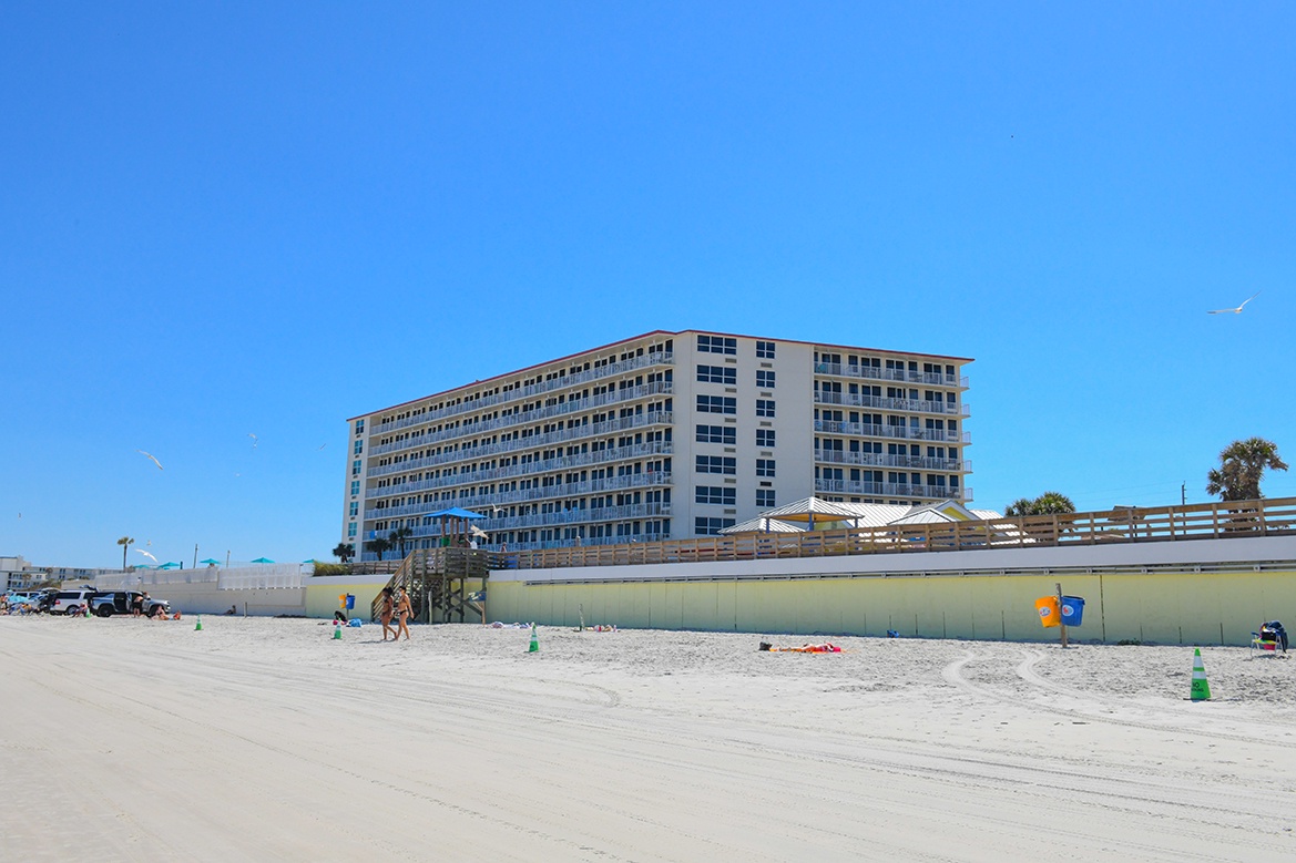 Beachfront property with direct sandy beach access and clear blue skies overhead.