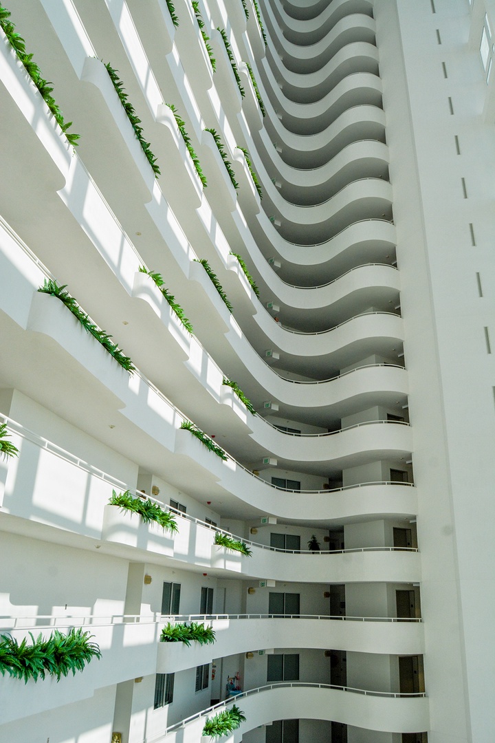 Step into a stunning modern hotel featuring curved balconies and tropical greenery creating an elegant, airy atmosphere for your getaway.
