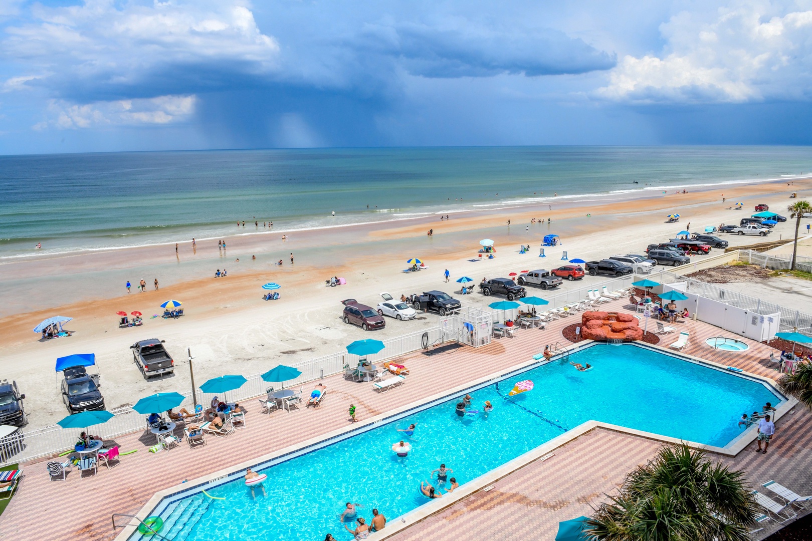 Beachfront property featuring a large swimming pool, sandy beach access, and convenient parking just steps from the ocean.