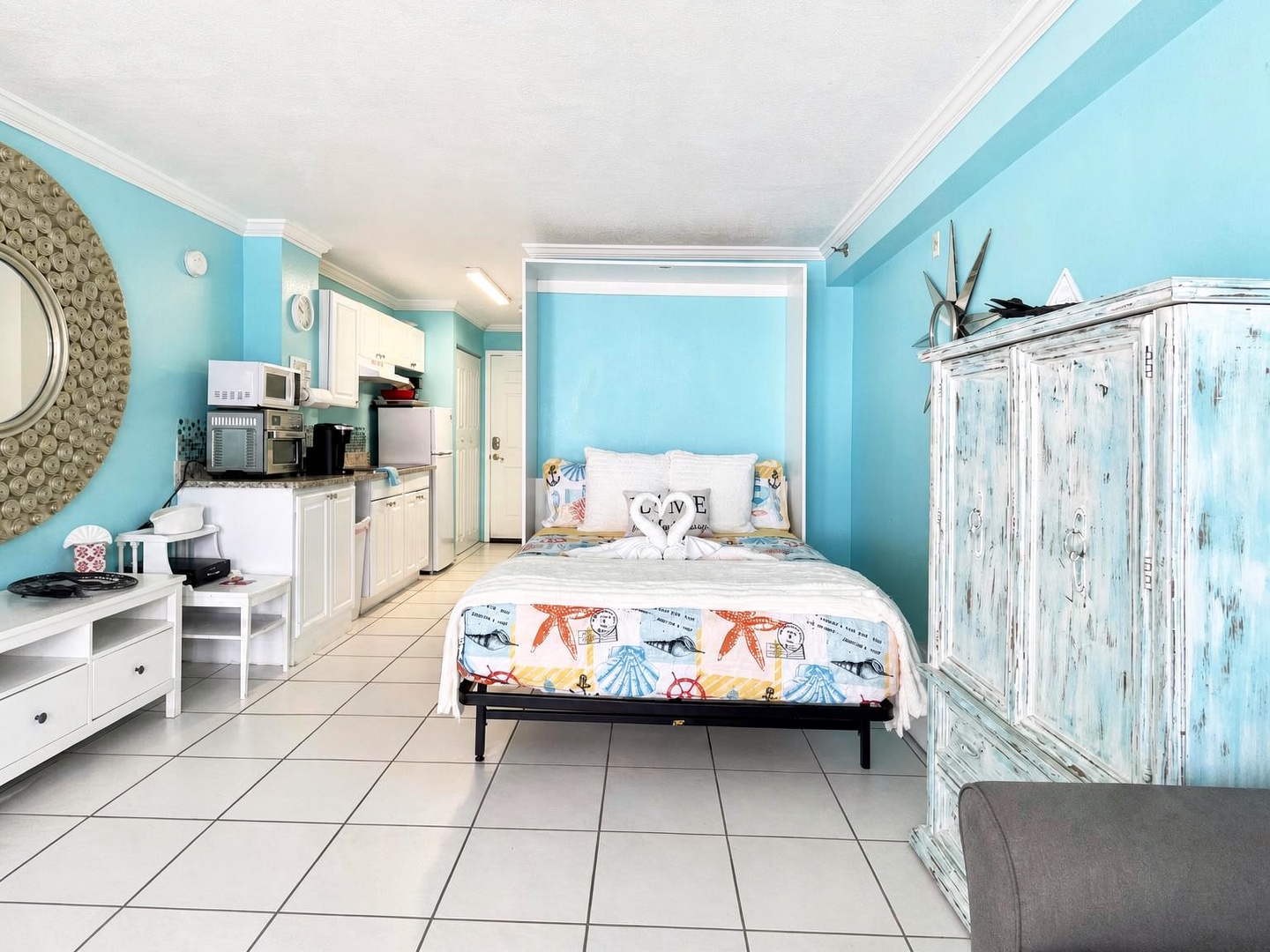 Relax in your bright, beachy studio where cheerful turquoise walls and coastal charm set the perfect vacation mood. Everything you need is at your fingertips—a cozy bed, full kitchenette, and charming weathered accents.