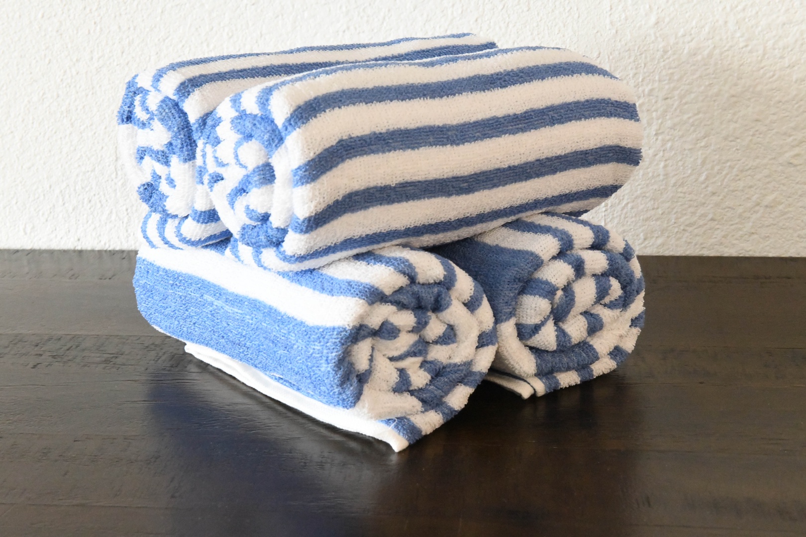 Plush towels in soothing blue and white await you, perfectly stacked and ready to wrap you in comfort after every shower or swim.