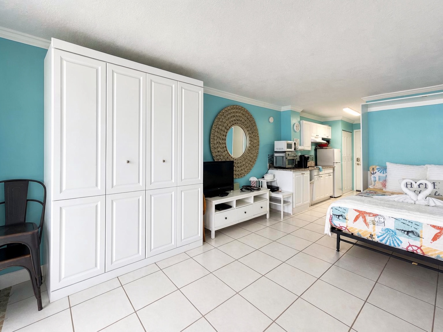 Your bright beachy studio blends rest and relaxation with cheerful turquoise walls, a cozy bed, and a fully equipped kitchenette ready for your coastal getaway.
