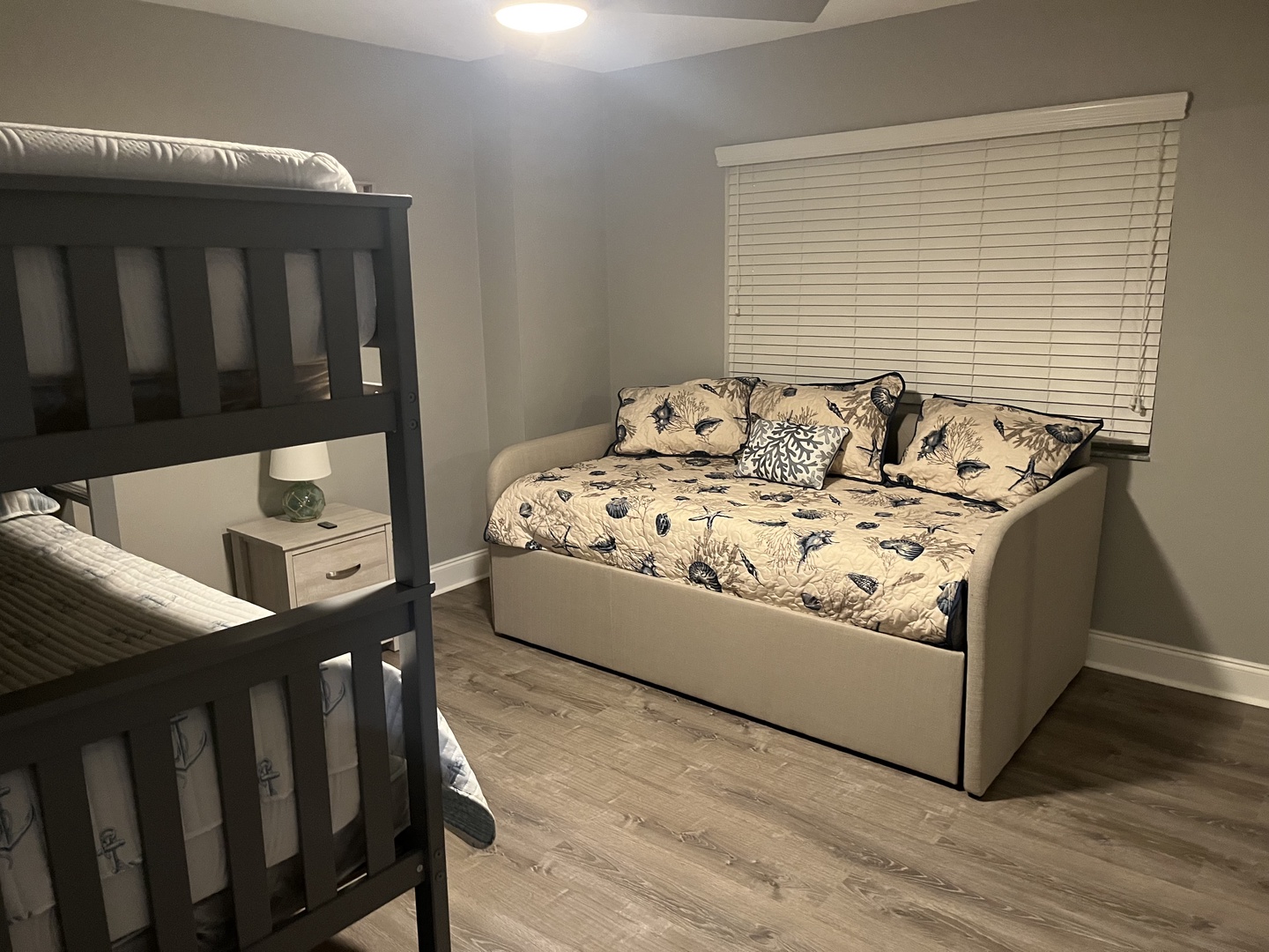 Your cozy bedroom features a comfortable daybed with floral linens and a convenient bunk bed, perfect for family stays.