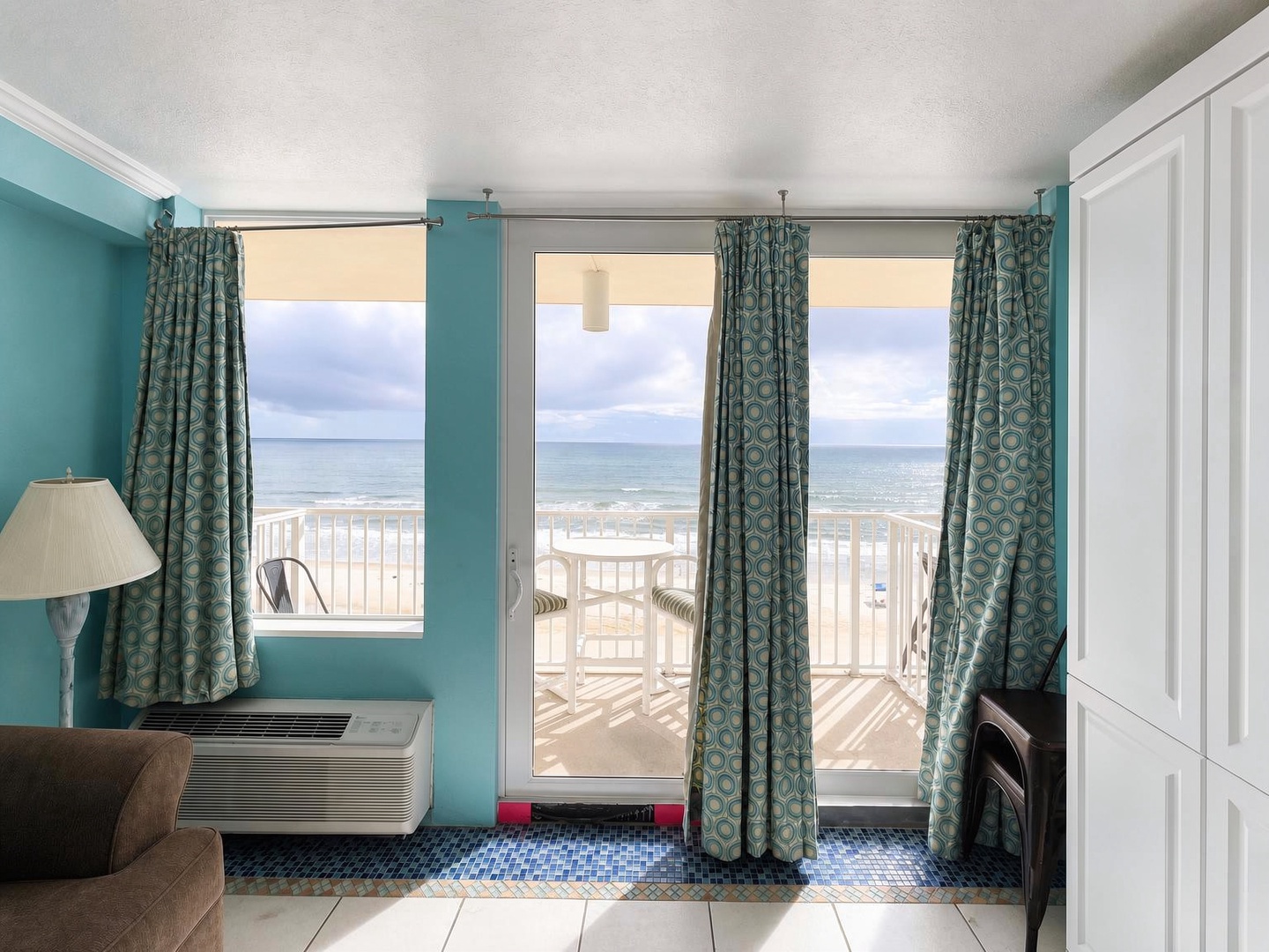Step through the glass doors to your private oceanfront balcony, where gentle waves and endless horizons await. Inside, cool coastal tones and comfortable furnishings create your perfect seaside retreat.